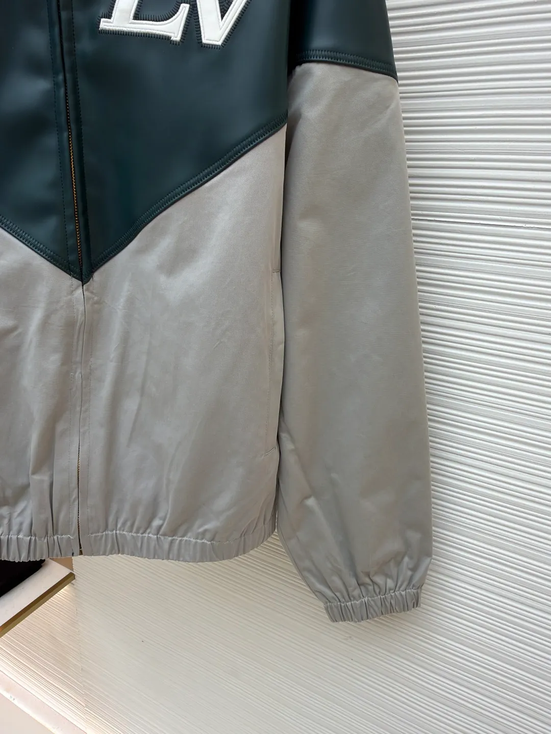 LOUIS VUITTON color-blocked sports long-sleeved jacket ●Original version: purchased and developed by 35590 ●Item number: 1681459-B80 ●Fabric: leather fabric ●Technology: intarsia production ●Color: gray-green splicing ●Version: fitted version ●Weight: about 800 grams ●Size: 46-48-50-52 ●Description: This jacket is made of high-quality genuine leather fabric. After special treatment, it feels soft and has a delicate luster. The contrasting color splicing design presents a fashionable layering. The stand-up collar structure is paired with a brand-customized metal zipper, and the zipper head is decorated with exquisite and luxurious pearls. The "LV" logo on the chest adopts three-dimensional leather embossing technology, with precise edge routing, strong three-dimensional effect and high recognition. The zipper pockets on both sides of the body are reinforced and sewn, which is practical and enhances the design. The splicing uses professional leather sewing technology, the stitch length is fine and even, and the ribbed design of the hem and cuffs fits the body shape. From the selection of genuine leather fabrics to the control of detailed craftsmanship, every process reflects LOUIS VUITTON's ultimate pursuit of craftsmanship precision and luxury style. It not only shows the high-end texture of leather items, but also highlights the brand design language through contrasting colors and three-dimensional logos. It is a fusion of leather craftsmanship and fashion design. The overall wiring is straight and delicate, the fabric is comfortable and soft, and the color is consistent without color difference. It can be matched with the same style to create a fashionable look and control various occasions. Customized accessories, complete with three standards, same style for men and women!